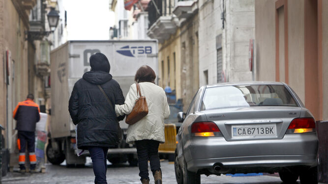 Dos mujeres pasean por una calle del casco antiguo con circulación.