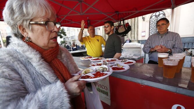 Una señora recoge su plato de ostiones en San Antonio.