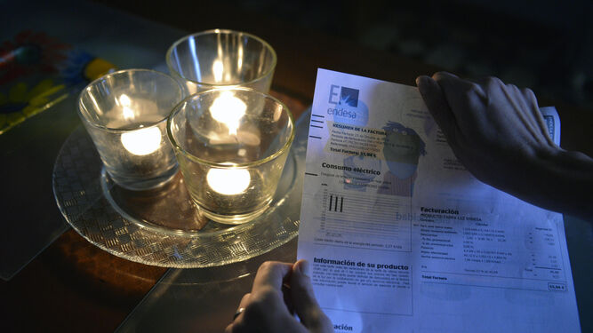 Una factura de la luz, junto a unas velas encendidas.