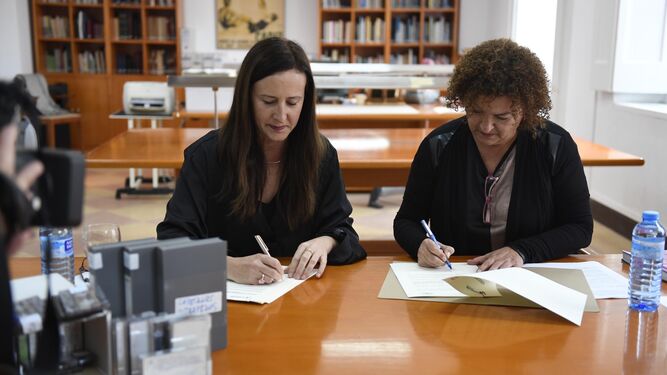 Remedios Palma (izquierda) y Eva Tubío firman el acuerdo en el Archivo ante algunos de los casetes y vídeos que serán digitalizados.