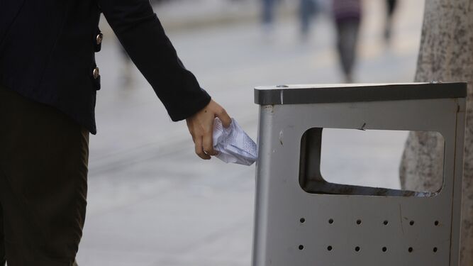 Una ciudadana arroja un papel a una papelera de la calle Real.