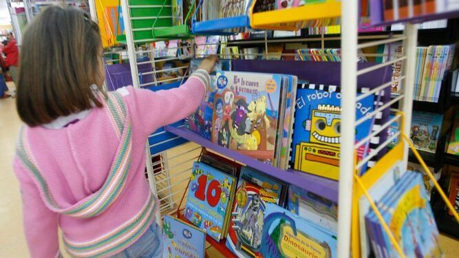 Una niña analiza las posibilidades que le ofrece una estantería de la librería infantil Qüentum.