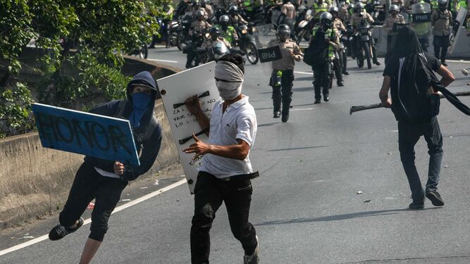 Tres manifestantes venezolanos huyen de las fuerzas armadas.