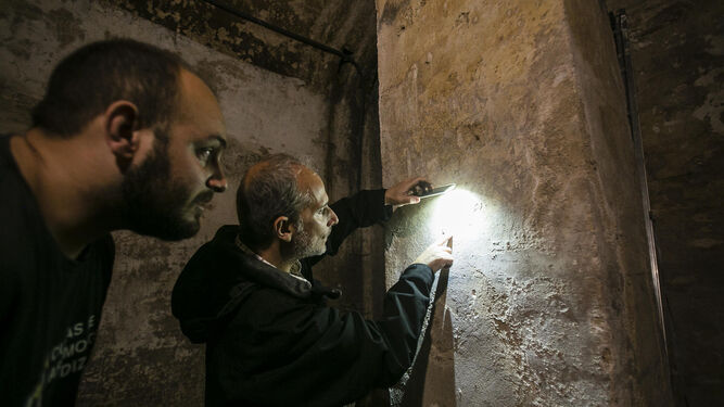 Eugenio Belgrano y un técnico municipal observan algunas inscripciones del aljibe, que parecen realizadas por los obreros de la casa.