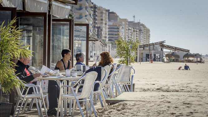 Varios clientes disfrutan de la terraza de un chiringuito de la playa de la Victoria.