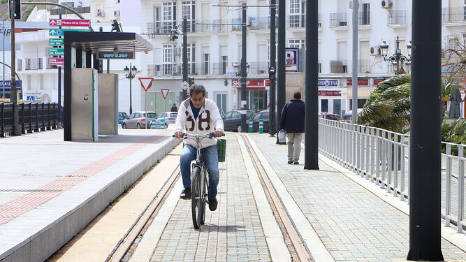 Un ciclista y un peatón circulan por la plataforma tranviaria en Chiclana.