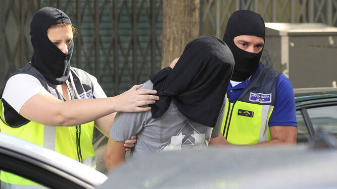 Dos agentes de la Policía Nacional trasladan a uno de los tres presuntos yihadistas detenidos el viernes en Madrid.