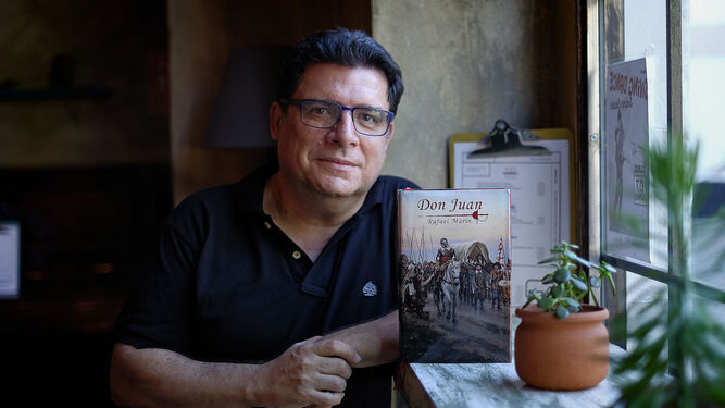 Rafael Marín junto a la portada de su novela, que reproduce 'El camino español' de Augusto Ferrer-Dalmau.