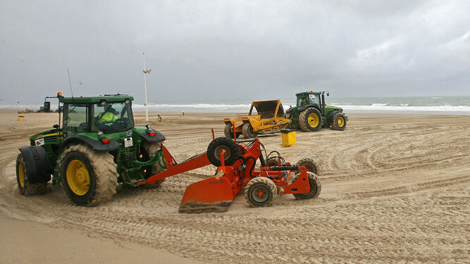 Trabajadores y maquinaria limpiando la arena de la playa Victoria.