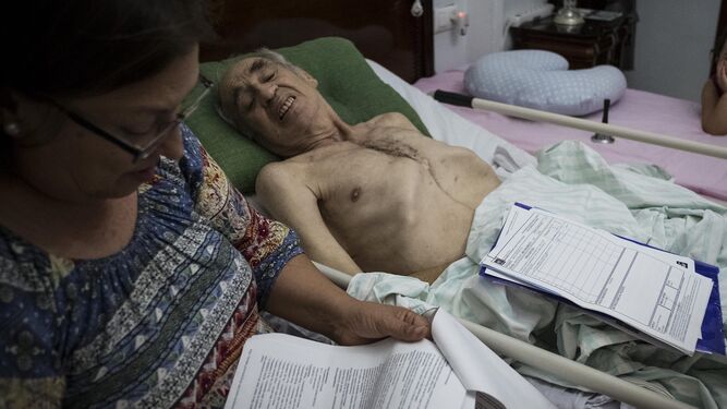 Rosario Muñoz, al pie de la cama de su marido, postrado después de once operaciones y la amputación de una pierna.
