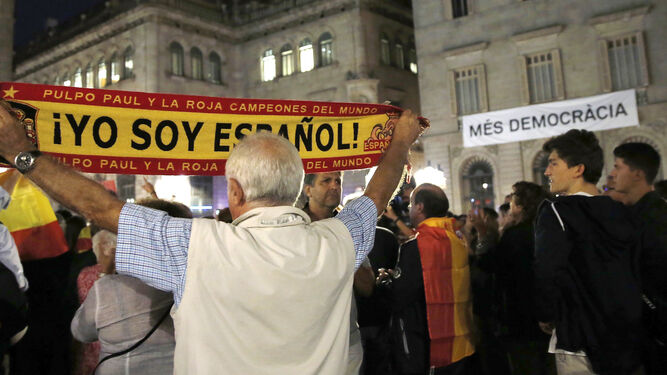 Un hombre sostiene una bandera con el lema "Yo soy español" delante del Ayuntamiento de Barcelona.