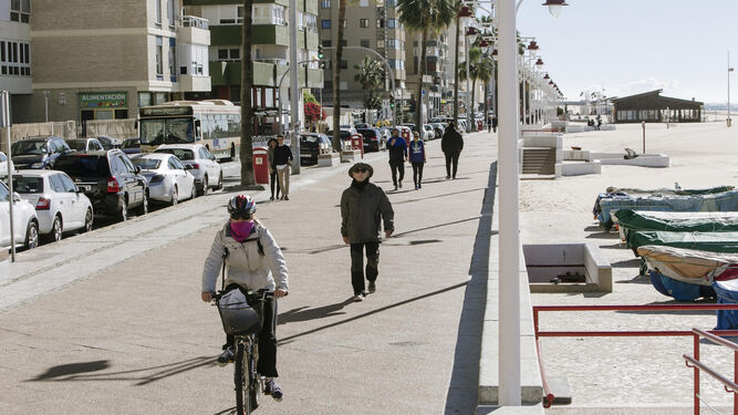 Un hombre monta en bicicleta por la acera del Paseo Marítimo junto a los peatones.