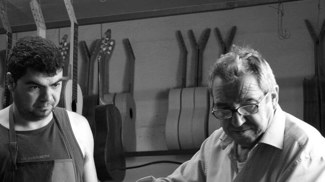 El artesano Valeriano Bernal prueba el sonido de una guitarra, en compañía de su hijo Rafael.