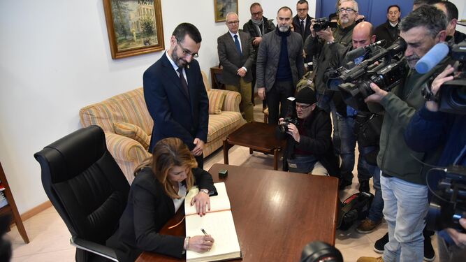 Susana Díaz firma en el libro de honor del Ayuntamiento de La Línea en presencia del alcalde, Juan Franco, rodeada de periodistas.