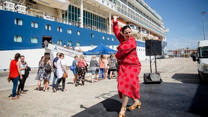 Una mujer bailando flamenco da la bienvenida a un grupo de cruceristas en el puerto gaditano.