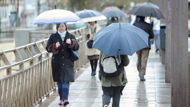 Viandantes se resguardan bajo un paraguas de la lluvia