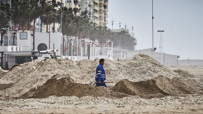 Un empleado camina entre los montones de arena.