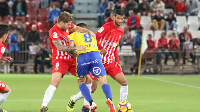 Perea busca espacio entre dos jugadores del Almería en el encuentro de la primera vuelta.