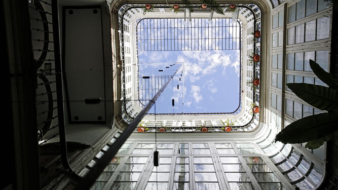 Torre de ascensor en el patio de una finca cubierta de vidrio espejado.