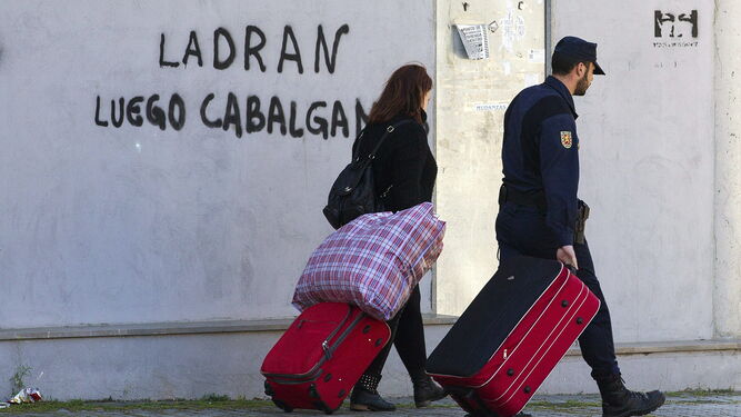 Un agente acompaña a una mujer desalojada de la Corrala la Utopía en Sevilla.