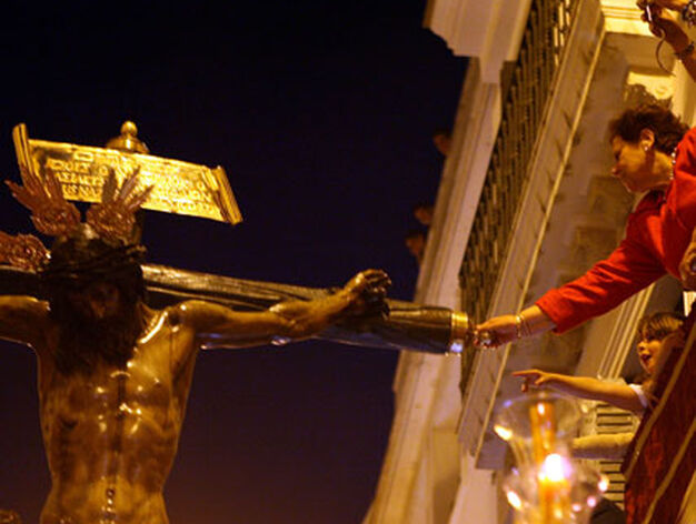 Una mujer toca al Cristo del Amor desde el balc&oacute;n de su casa.

Foto: Juan Carlos Mu&ntilde;oz