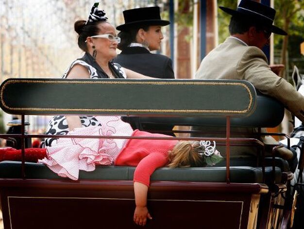 Una ni&ntilde;a vestida de gitana, derrotada ya a estas alturas de la Feria, dormida en un enganche. 

Foto: Pascual