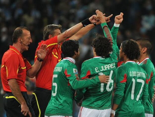 Los jugadores mexicanos reclaman al linier y al &aacute;rbitro la anulaci&oacute;n del primer gol de T&eacute;vez por fuera de juego. / AFP