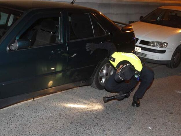 Un polic&iacute;a busca el arma del crimen bajo el coche.

Foto: Antonio Pizarro