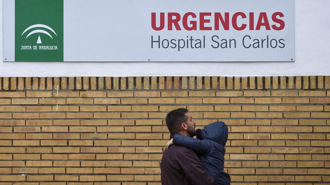 Un hombre con un pequeño en brazos se dirige ayer al acceso del servicio de Urgencias del hospital de San Carlos.