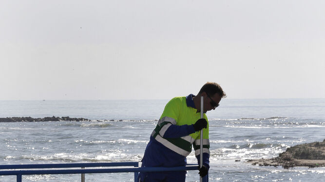 Un operario de Aqualia realiza mediciones en la depuradora de Barbate con el océano Atlántico al fondo.