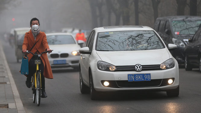 Una mujer transita con una mascara debido a la bruma por contaminación en Pekín.
