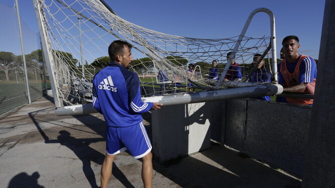 Los jugadores del Cádiz tratan de sortear un obstáculo al trasladar una portería de un campo a otro en El Rosal.