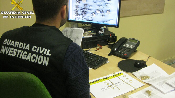 Un guardia civil observa en el ordenadores las joyas robadas.