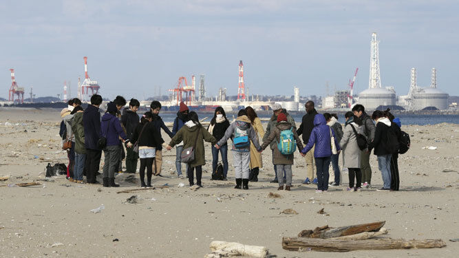 Un grupo de personas reza por las víctimas del terremoto y el posterior tsunami en la playa de Arahama, en Sendai.