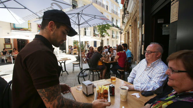 Un camarero atiende a unos turistas en un local del centro de Cádiz.