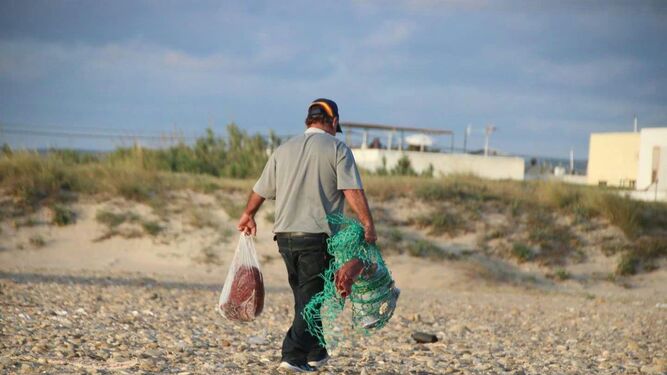 Un hombre se vale de bolsas de plástico y redes para transportar el atún.