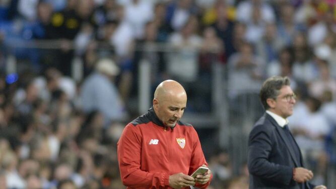 Jorge Sampaoli revisa su móvil durante el partido en el Bernabéu.