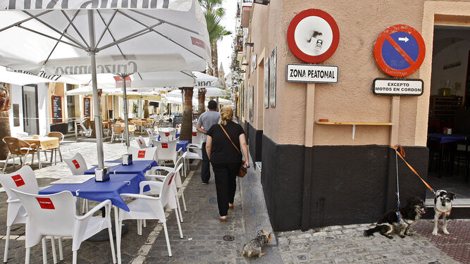Unos vecinos atraviesan la zona peatonal de la que advierte la señal de tráfico en la calle de La Palma, repleta de terrazas de bares.