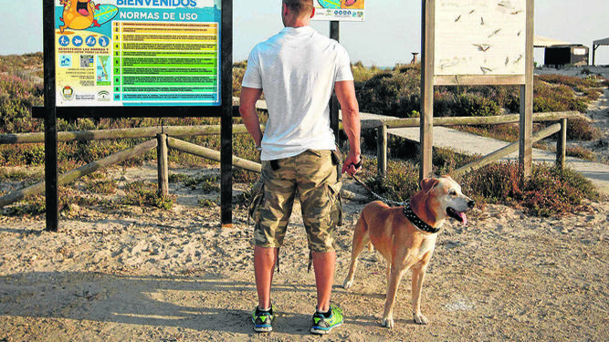 Un usuario con su perro ante el cartel informativo con las normas de uso de la playa canina en Camposoto, en una imagen del año pasado.