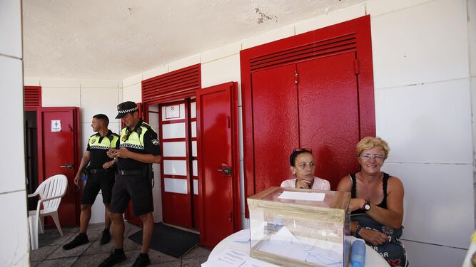 Trabajadoras de los Módulos de Playa custodian la urna de la votación junto a la Policía Local.