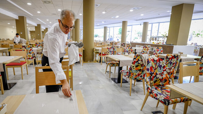 Un camarero viste una mesa en la zona de buffet del hotel Alegria Costa Ballena.