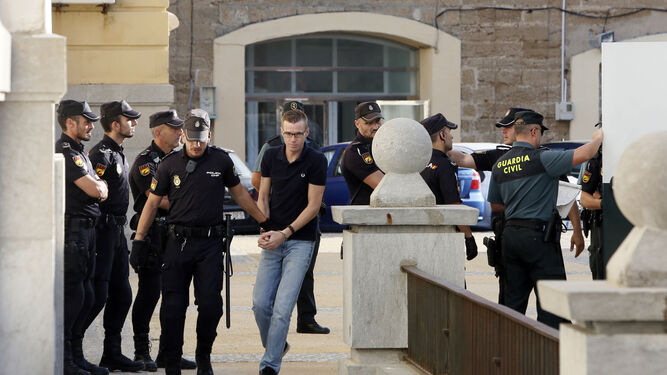Un acusado escoltado por la policía y la guardia civil mientras accede al Palacio de Justicia.