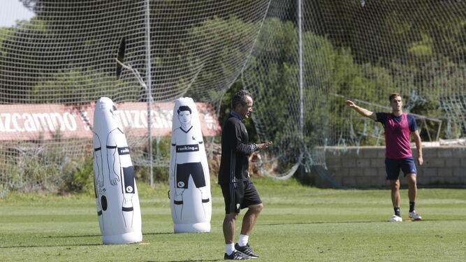 Álvaro Cervera camina sobre el campo de entrenamiento mientras Brian, al fondo, realiza una indicación.