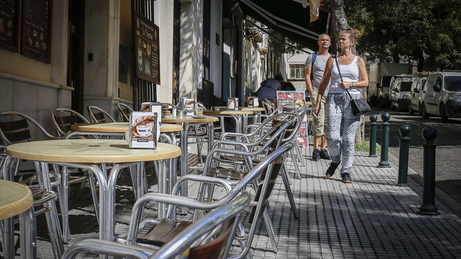 Dos turistas pasando ayer junto a la terraza vacía de una cafetería en el centro de Cádiz.