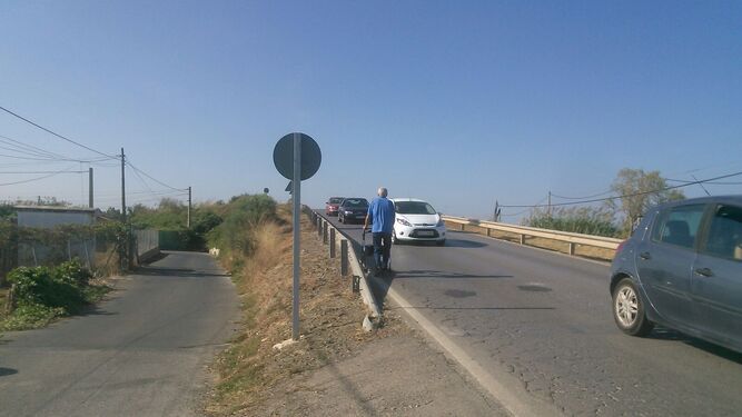 Un peatón camina junto a los vehículos en la carretera de El Marquesado.