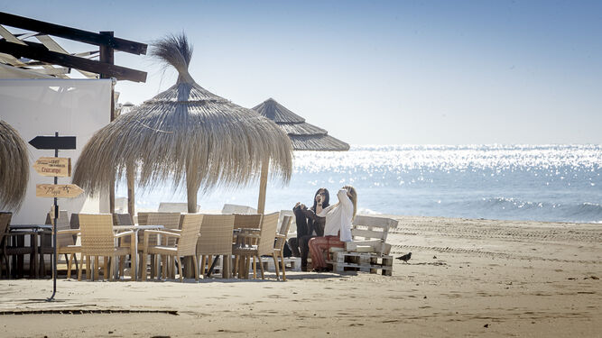 Dos clientes disfrutan de un día soleado en la terraza de un chiringuito de la playa de La Victoria.