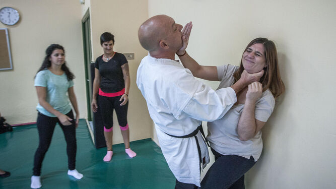 El monitor muestra con una de las alumnas cómo defenderse ante un agresor que agarra del cuello.