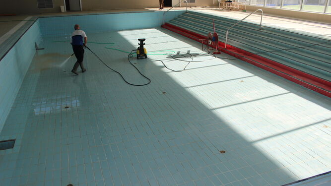 Un operario municipal limpia uno de los vasos del complejo de piscinas.