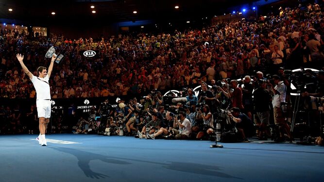 El tenista suizo Roger Federer saluda al público de Melbourne levantando el trofeo recién conquistado, el noveno que se lleva en el mismo escenario.