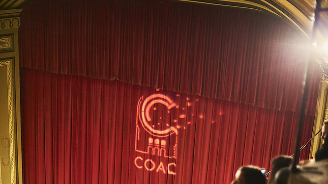 El telón del Gran Teatro Falla con el logo del COAC sobreimpresionado.